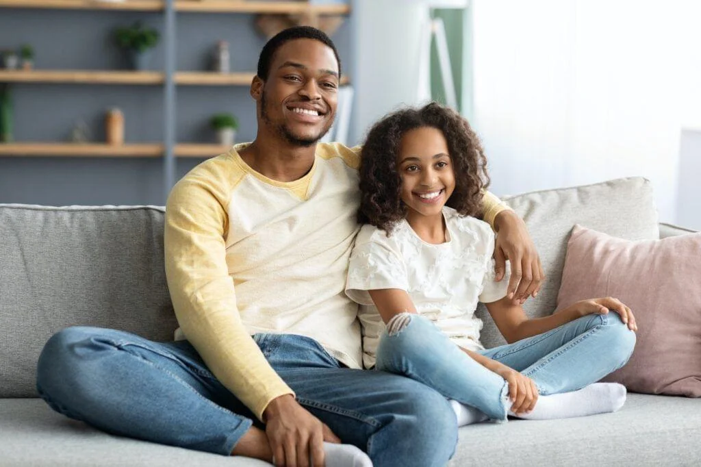 Adorable black family father and daughter watching movie together